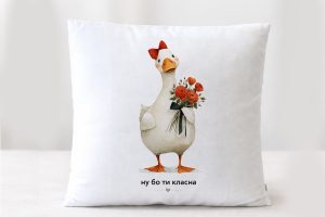 Подушка подарункова плюшева біла з малюнком білої гуски з червоним бвнтиком,яка тримає букет червоних квітів, внизу напис: Ну бо ти класна.Розмір 35*35